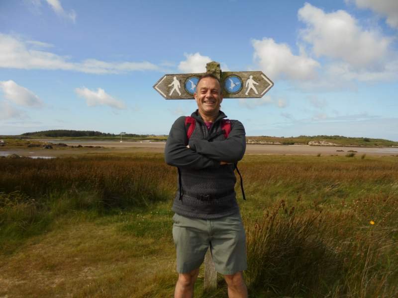 Jez standing in front of wales coast path signpost near RAF Valley